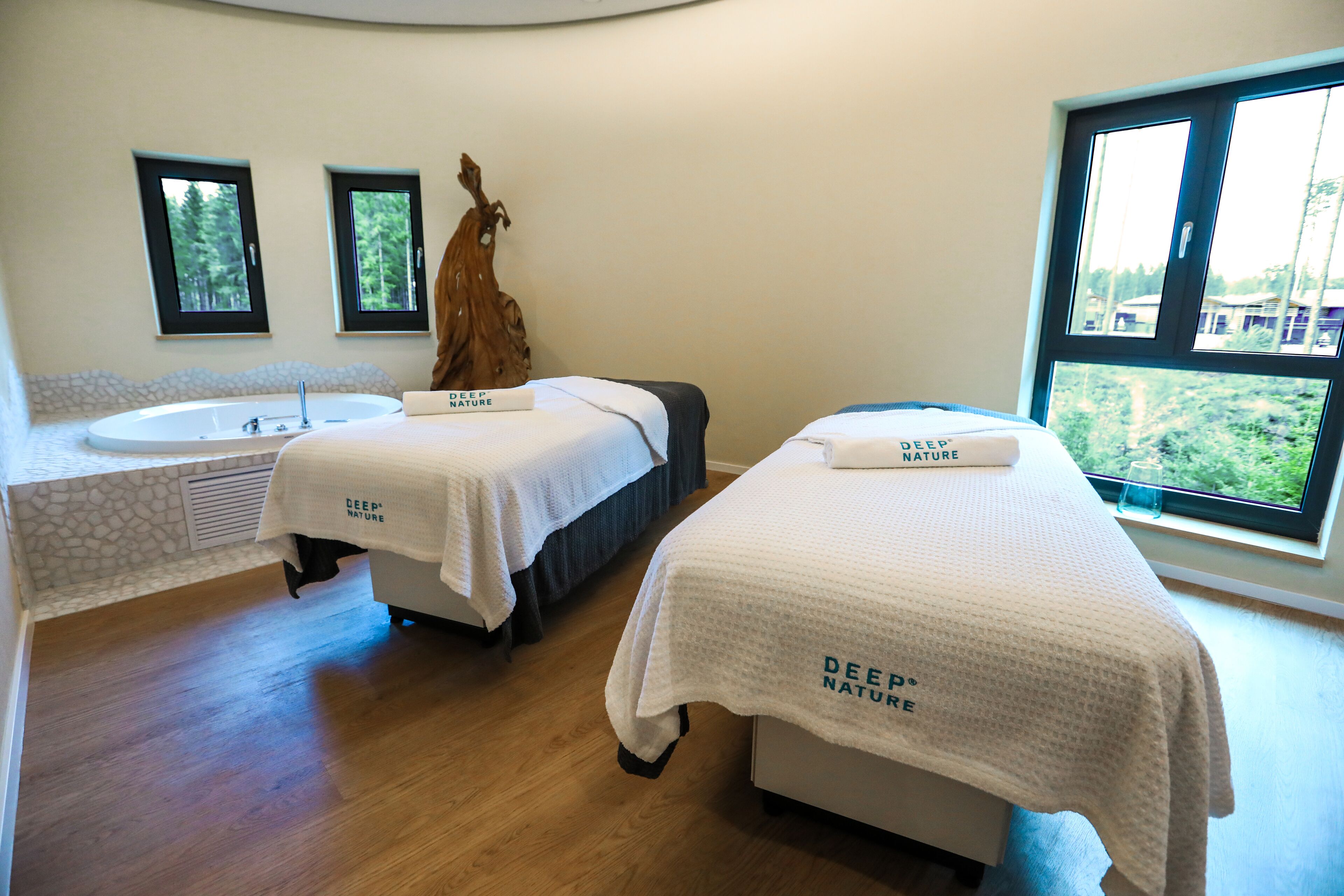 Ein Spa-Raum mit zwei Betten, einem großen Fenster und einer Steinwand.