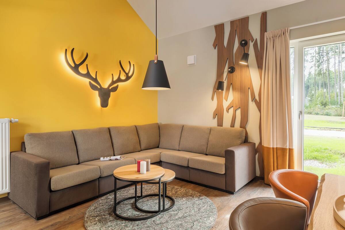 A modern living room with a sectional sofa, a round coffee table, and a deer head wall decoration.