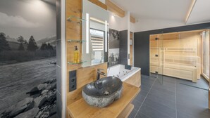 A modern bathroom with a stone sink, wooden vanity, and a large mirror. - Center Parcs Bungalowpark Allgäu (Leutkirch im Allgau)