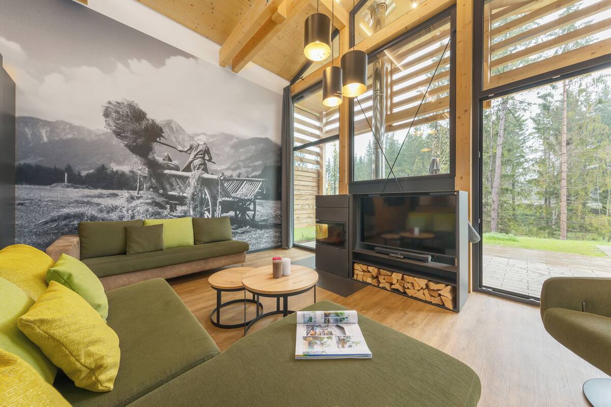 A modern living room with a large flat-screen TV, a green sofa, yellow cushions, a fireplace, and a mural of a person skiing.
