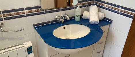 A bathroom with a blue sink, white cabinets, a mirror, and a towel rack.