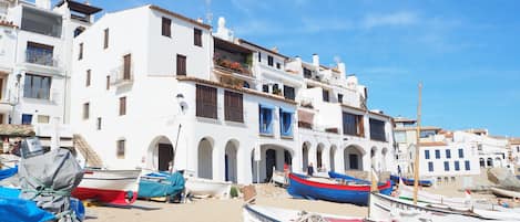 A coastal town with white buildings, a sandy beach, and several boats.