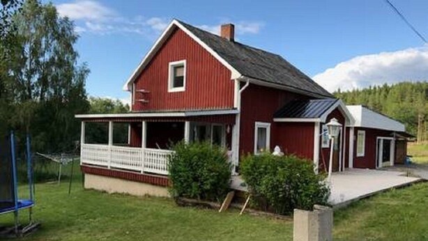 A red house with a white porch and a small attached garage.