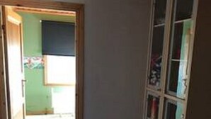 A room with a purple carpet, a wooden door, and a cabinet with glass doors.