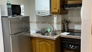 Cozinha compacta com geladeira, micro-ondas, fogão e pia.