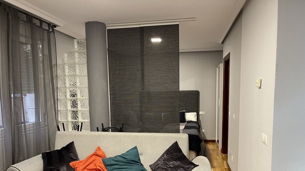 Uma sala de estar com um sofá cinzento, uma mesa de centro e um painel decorativo na parede.