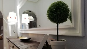 Una habitación bien iluminada con un árbol en maceta, un cuenco y una tableta sobre una encimera de madera.