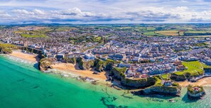 An aerial view of a coastal town with a beach, residential areas, and a prominent church.