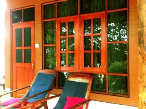 A wooden room with large windows and two lounge chairs.