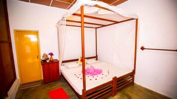 Ein Bett mit Himmelbett, ein Nachttisch in Rot mit Blumenvase und ein roter Teppich auf dem Boden.