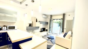 A modern kitchen with a microwave, toaster, and a coffee machine. There is a dining area with a sofa and a coffee table.