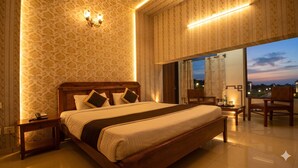 Un dormitorio amplio con una cama grande, mesitas de noche, una silla y vistas al exterior.