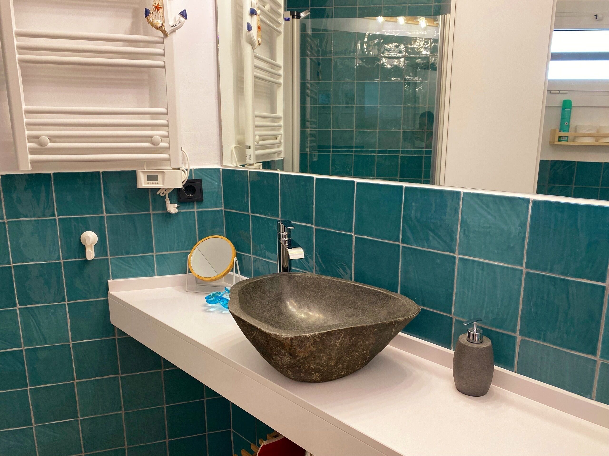 Une salle de bain avec un comptoir blanc, un grand lavabo, un miroir et un porte-serviettes.