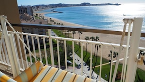 A balcony with a striped cushion, overlooking a beach and cityscape. - Stunning beachfront penthouse (Calonge)
