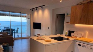 A modern kitchen with a central island, a dishwasher, and a flat-screen TV. - Stunning beachfront penthouse (Calonge)