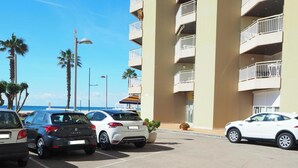 A parking lot with several cars parked in front of a building with balconies. - Stunning beachfront penthouse (Calonge)