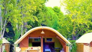A single tent with a porch, a table, and chairs, surrounded by trees. - Camping des Rives des Corbieres (Leucate)