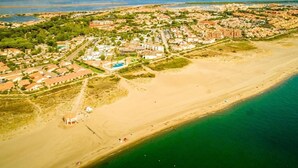 An aerial view of a coastal town with a beach, residential areas, and a body of water. - Camping des Rives des Corbieres (Leucate)