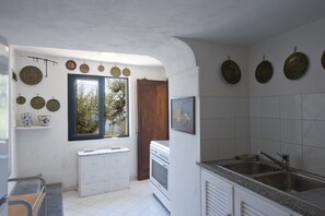 Una cocina con armarios blancos, horno empotrado, lavamanos y platos decorativos en la pared.