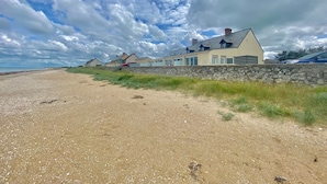 En fastighet vid kusten med en stenmur och flera hus längs stranden.