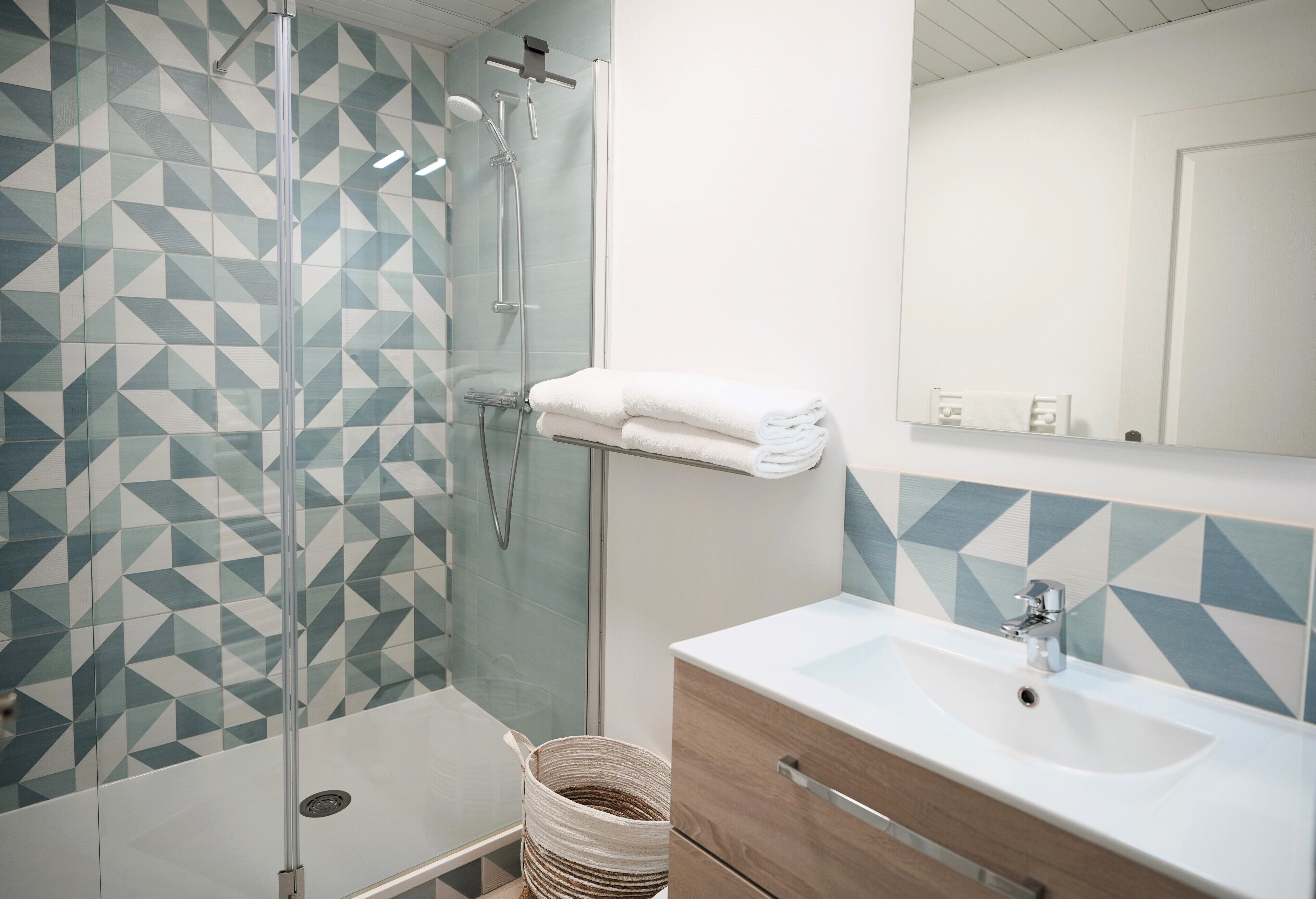 A bathroom with a shower, a sink, and a mirror.