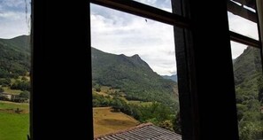 Une vue à travers une fenêtre sur un paysage de montagne, comprenant une maison et un champ.