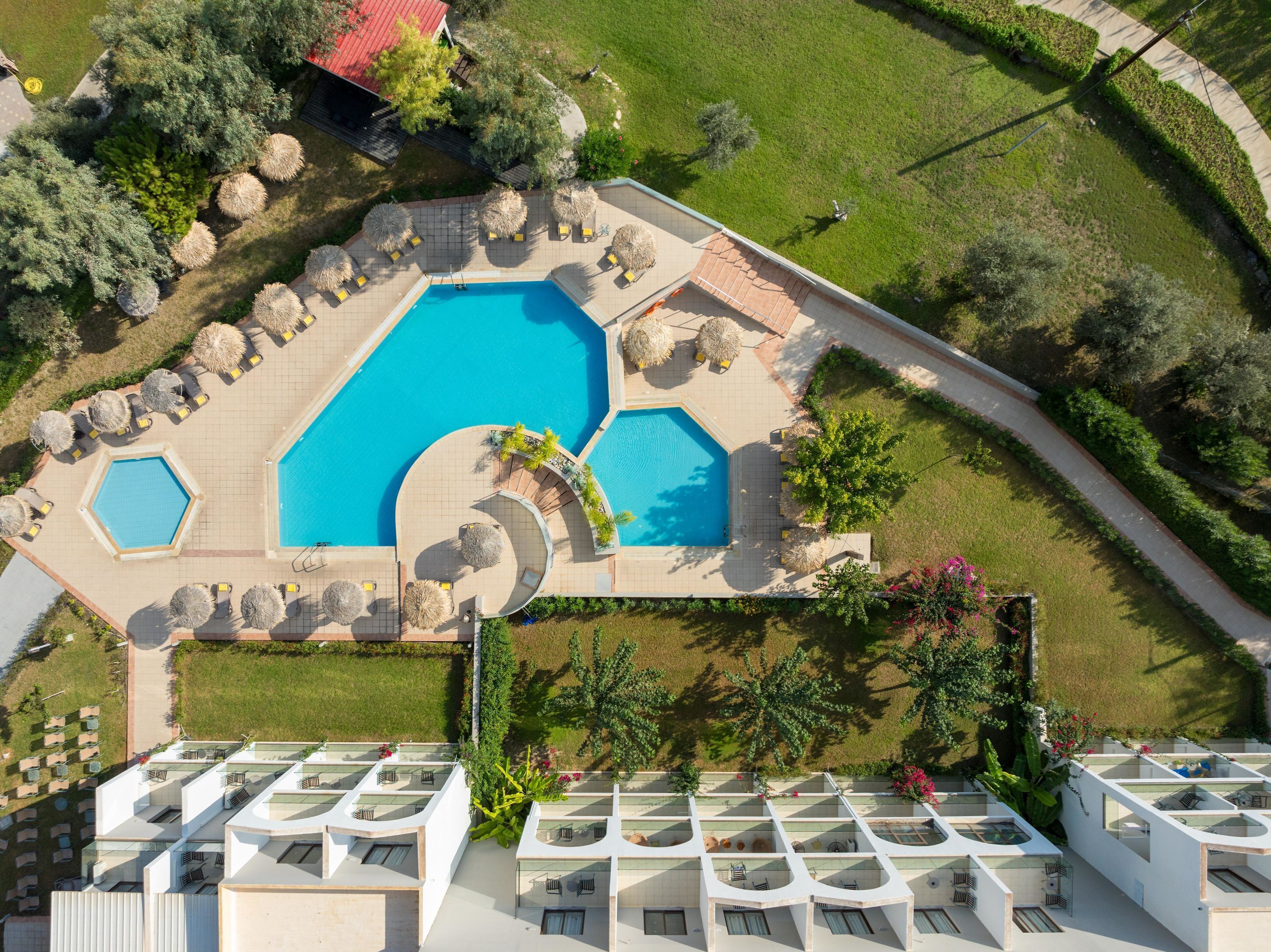 Vue aérienne d’un hôtel doté d’une piscine centrale, de plusieurs espaces de détente et d’un jardin sur le toit.