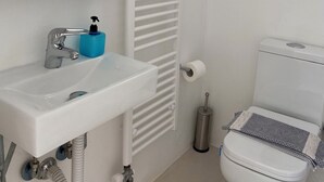 Et badeværelse med hvid vask, spejl, toilet og radiator.