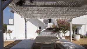 Et overdækket udendørs opholdsområde med bænke og en pergola.