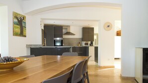 Eine moderne Küche mit dunklen Schränken, einer Mikrowelle und einem Backofen. Ein Esstisch mit Stühlen und eine Schale mit Tannenzapfen steht dort.