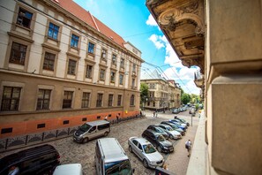 A street view with parked cars and a building with classical architecture. - Post House Rooms (Lviv)