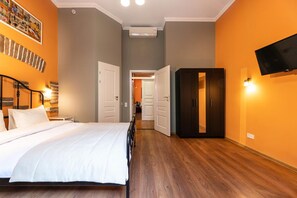 A hotel room with a bed, a wardrobe, a television mounted on the wall, and a hallway leading to another room. - Post House Rooms (Lviv)