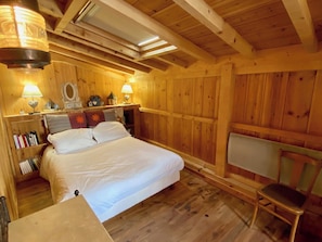 A wooden room with a bed, a chair, and a shelf with books. - Idyllic chalet near the beach in Cap Ferret A0337 (Lège-Cap-Ferret)
