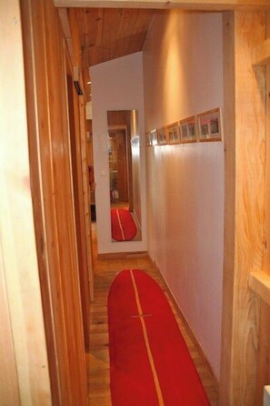 Un estrecho pasillo con paredes de madera y alfombra roja.