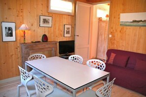 Una habitación con paneles de madera, una mesa de comedor, sillas, un televisor y un sofá.