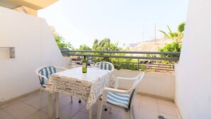 A balcony with a table and chairs, a bottle of wine, and a view of the beach and palm trees. - Studio Hotel Apt, in Costa Adeje, Few Minutes Walk To Beach, Shops & Bars (Costa Adeje)
