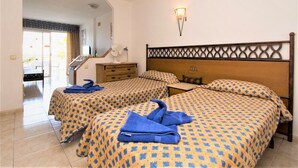 A hotel room with two beds, a wooden headboard, a small table, and a fan. - Studio Hotel Apt, in Costa Adeje, Few Minutes Walk To Beach, Shops & Bars (Costa Adeje)