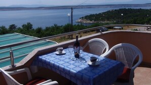 A balcony with a table set for two, overlooking a body of water and a distant landscape. - Apartment in Dramalj with Seaview, Balcony, Air condition, WIFI (4623-10) (Dramalj)