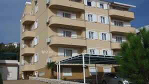A multi-story residential building with balconies, a covered parking area, and a stone wall. - Apartment in Dramalj with Seaview, Balcony, Air condition, WIFI (4623-10) (Dramalj)