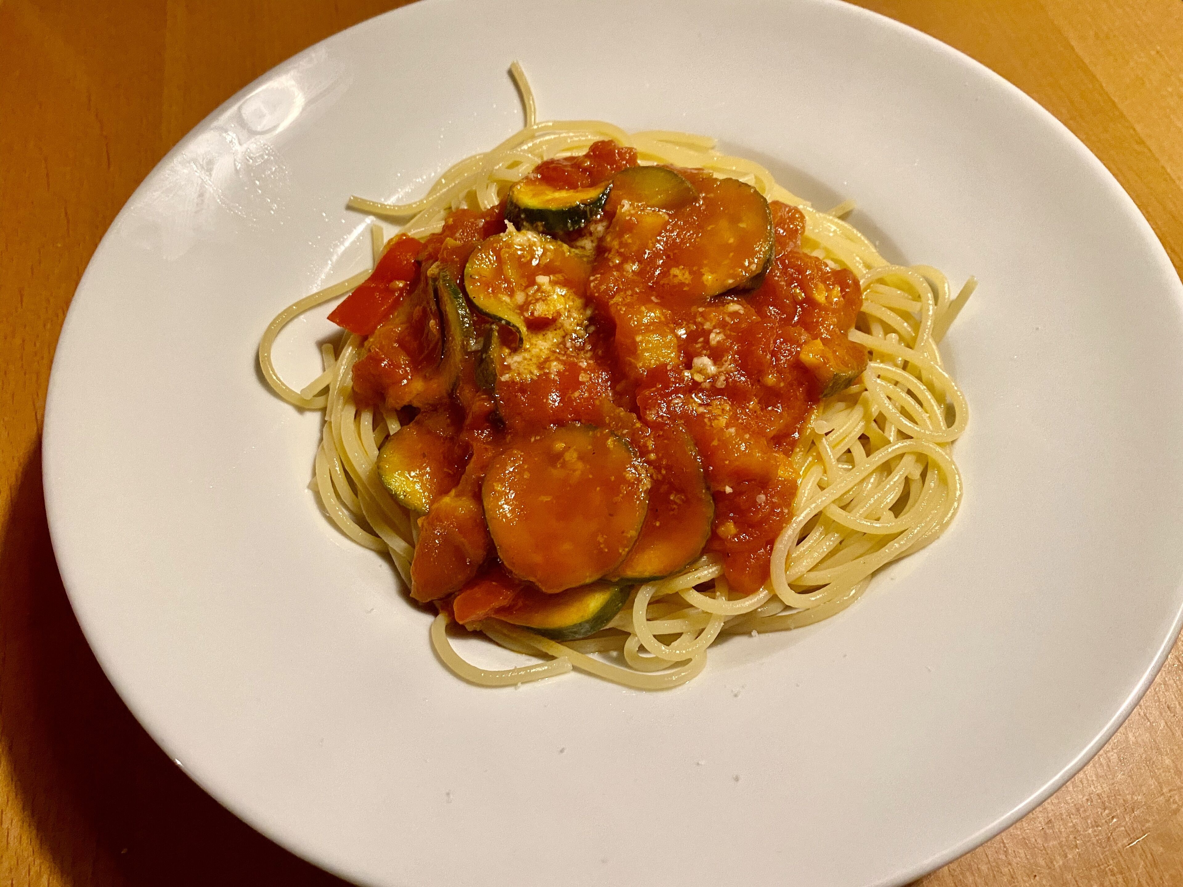 A plate of spaghetti with tomato sauce and vegetables.