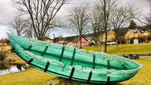 A green boat sculpture on a grassy area with houses in the background. - Pension Waldblick (Spiegelau)