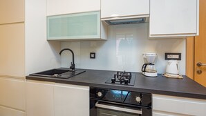 Een moderne keuken met een zwart aanrecht, een ingebouwde oven, een koffiezetapparaat en een glazen kast.