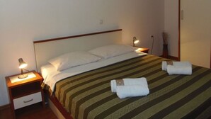 Una cama bien hecha con un edredón a rayas y dos toallas enrolladas encima.