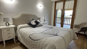 A bedroom with a bed, bedside tables, a nightstand, a chair, and a window with curtains. - Apartment for 4 people (Usurbil)