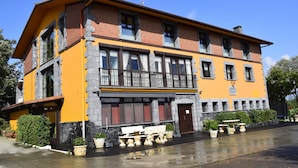 A two-story building with a yellow facade, stone accents, and a balcony with a railing. - Apartment for 4 people (Usurbil)