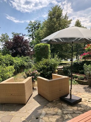 An outdoor seating area with wicker furniture and a large umbrella. - Vacation apartment in the Villa Graf von Pfeil on the banks of the Elbe (Neustadt)