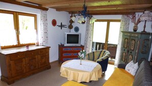 A cozy room with a bed, a wooden dresser, a television, and a chair.