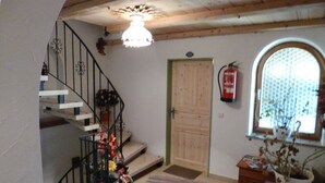A staircase with a railing, a wooden door, a fire extinguisher, and a window with a view.