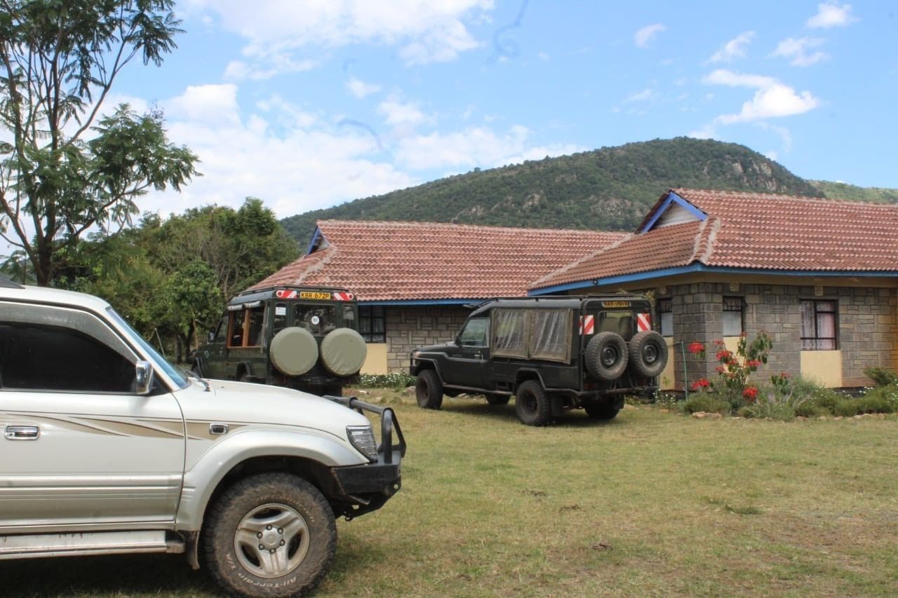 Un edificio de piedra con techo de tejas rojas y un vehículo estacionado al frente.