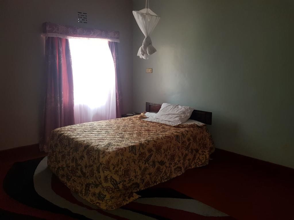 A bedroom with a bed, curtains, a mosquito net, and a wall socket.